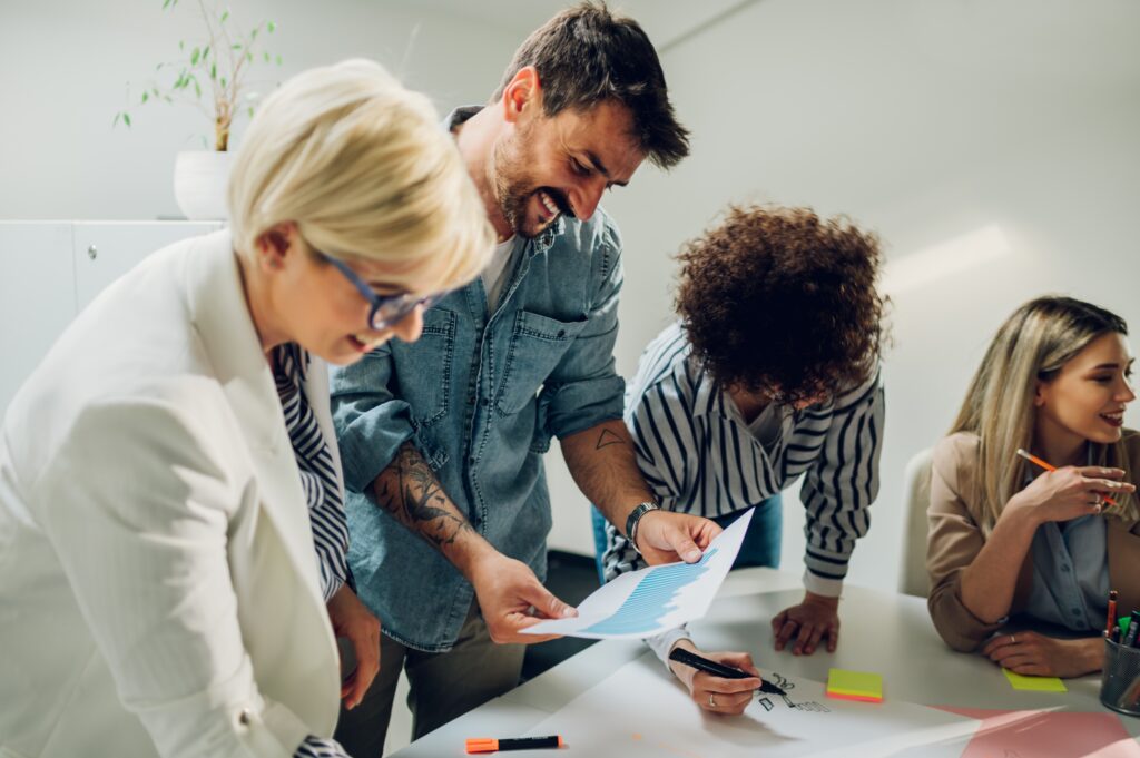 Diverse group of marketers analyzing graphs and discussing brand strategy, exemplifying a hands-on approach to crafting impactful messages.